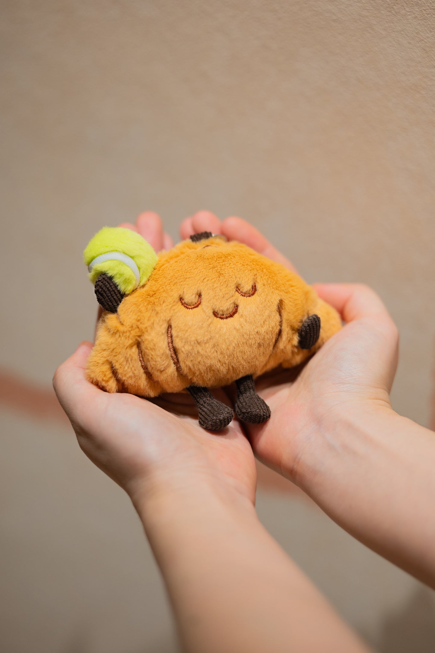 Close-up of hands holding croissant plush tennis doll