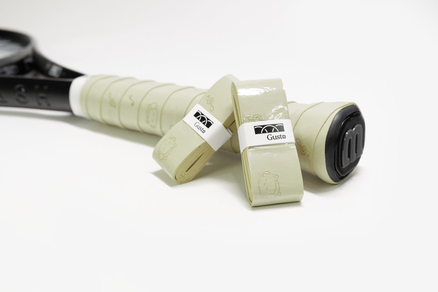 Light olive green PU tennis overgrip with cat and music note design, shown on racket handle.