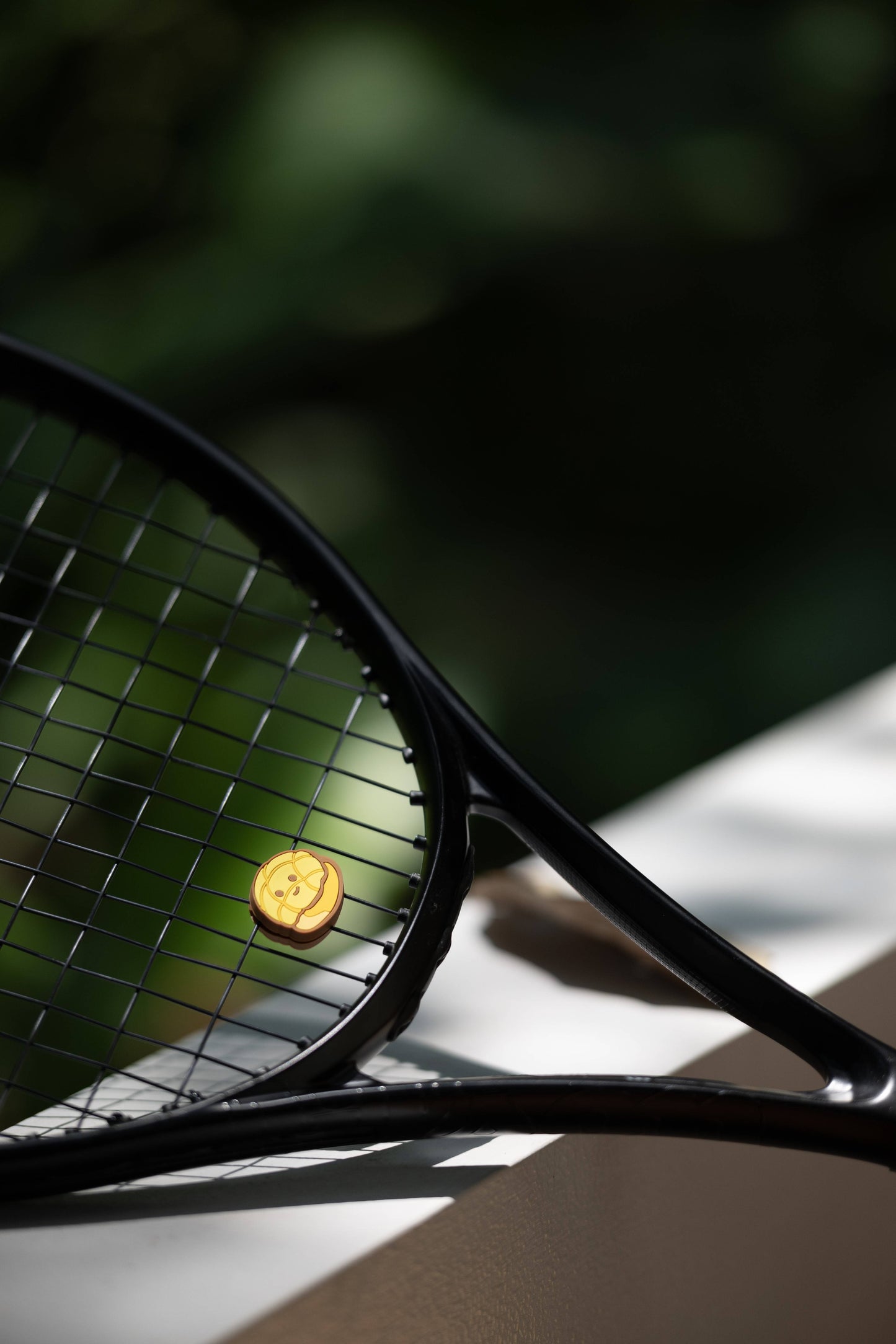 Model holding pineapple bun shaped tennis vibration dampener, cute bakery series tennis accessory