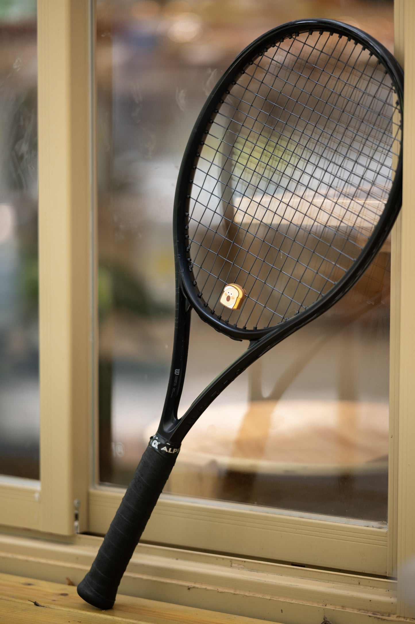 Model holding toast shaped tennis vibration dampener, bakery series tennis accessory