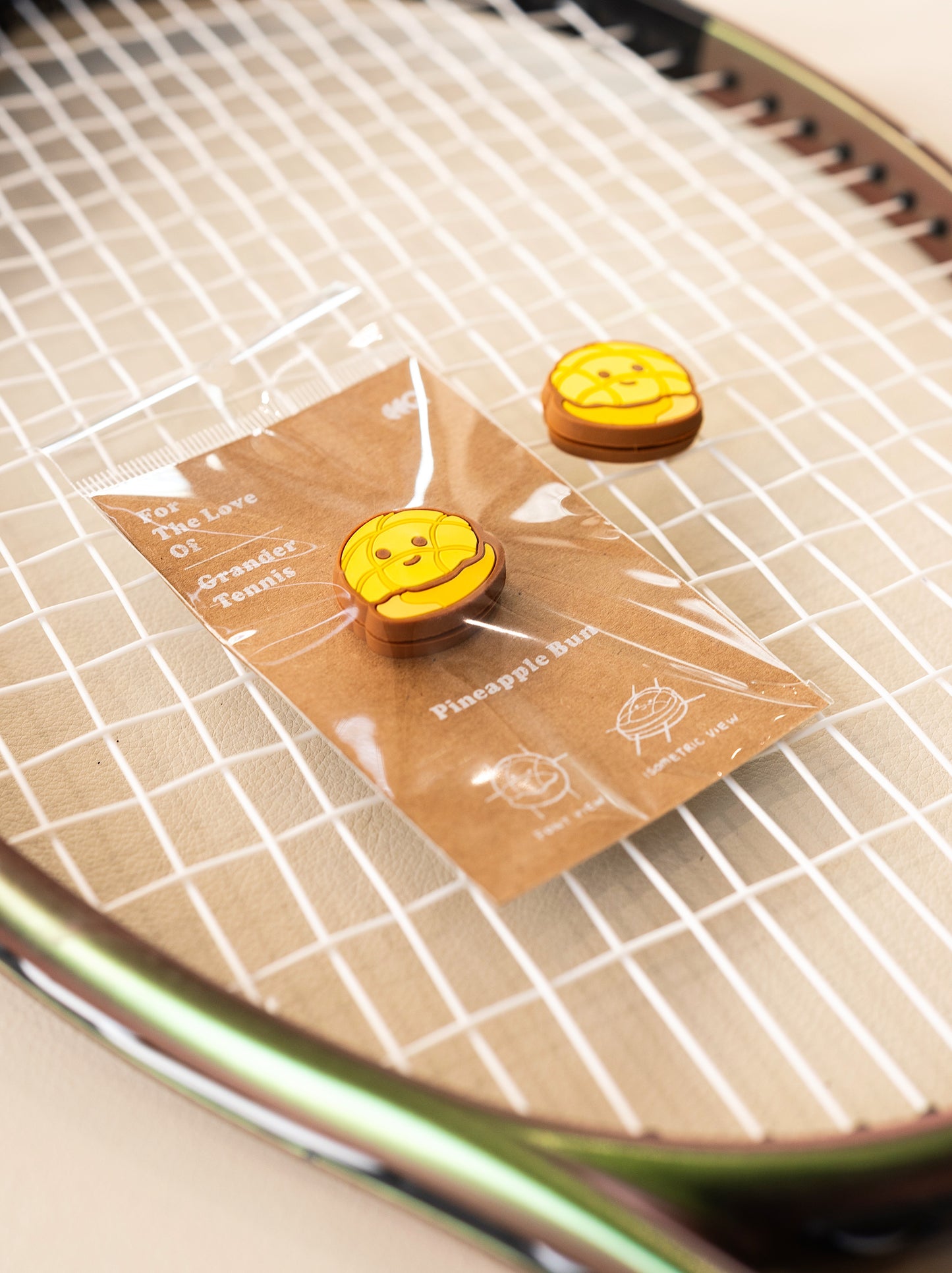 Pineapple bun tennis dampener placed on tennis racket strings, bakery series vibration absorber