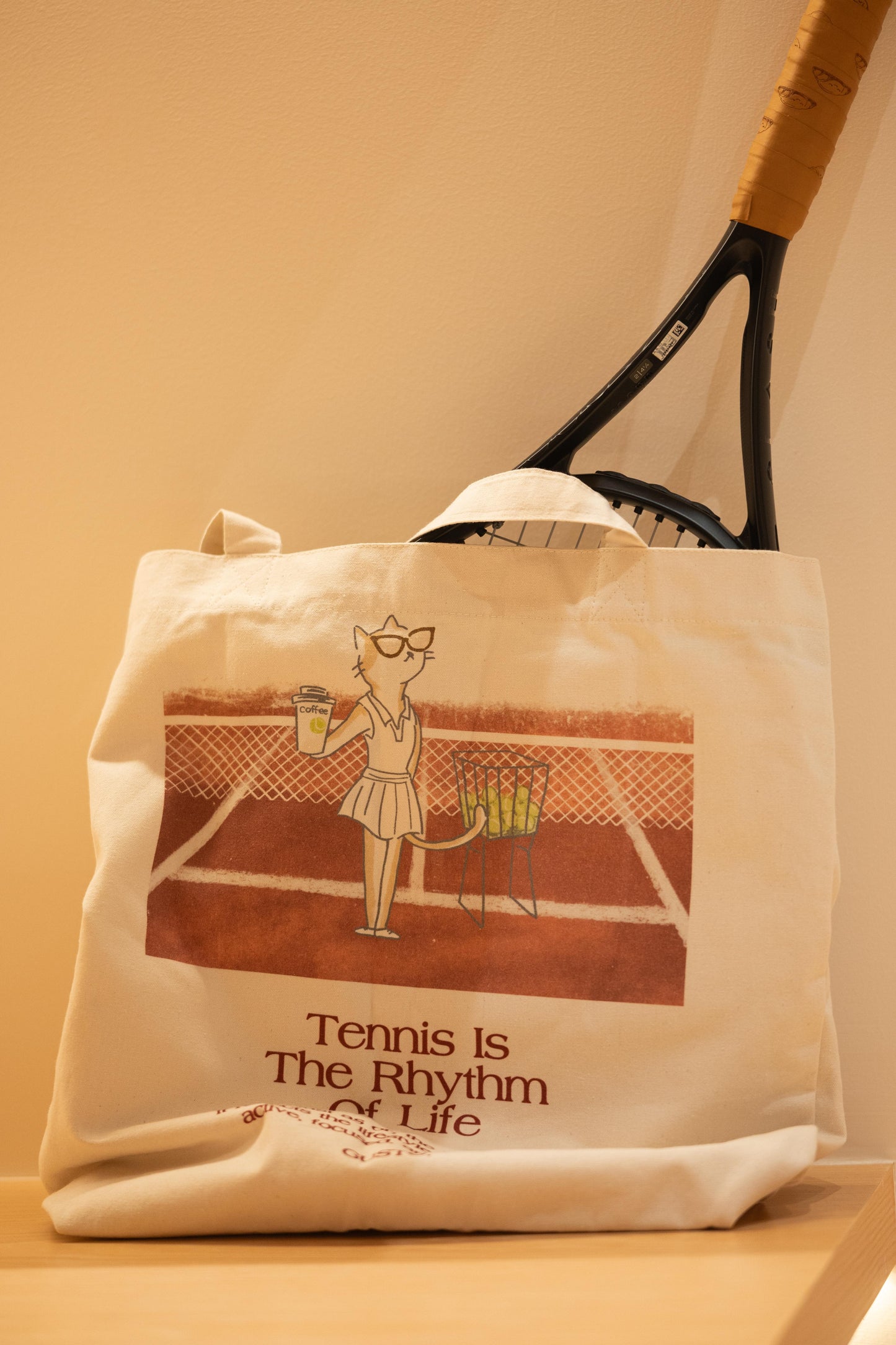 Red tennis canvas tote bag with stylish cat design, holding a tennis ball, placed on a display shelf