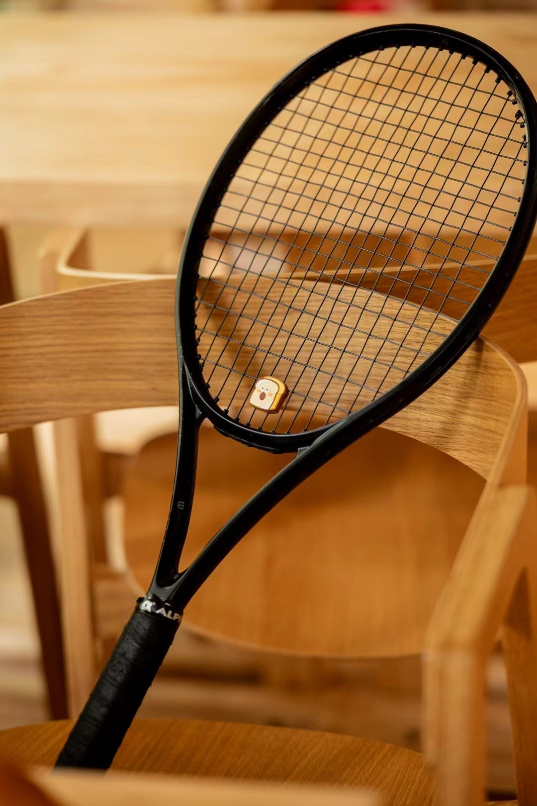 Close-up of toast shaped tennis dampener placed on wooden surface, bakery series design