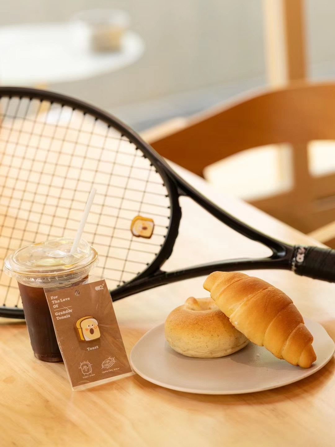 Toast shaped tennis racket dampener photographed in café lifestyle setting with coffee cup