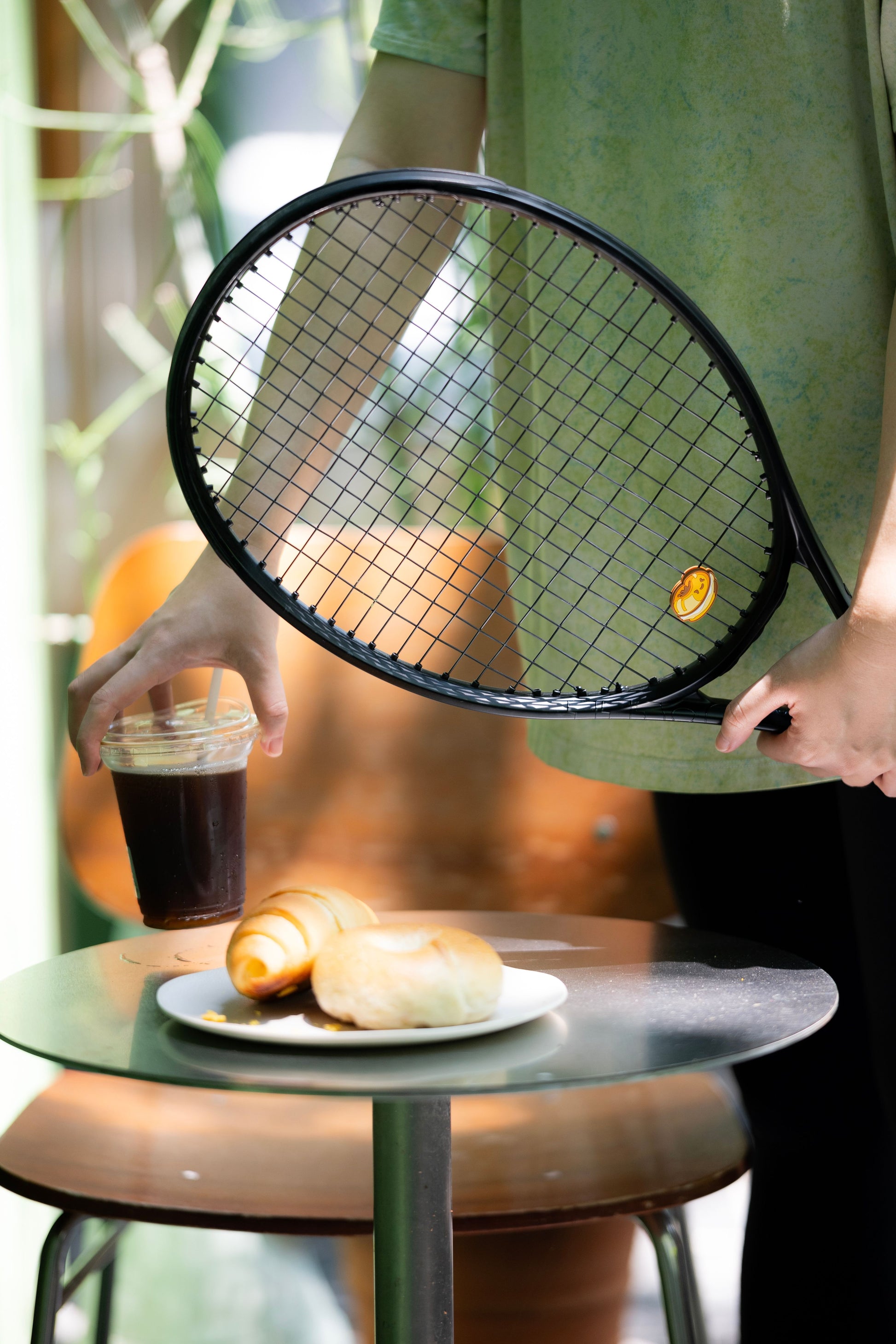 Bagel shaped tennis racket dampener photographed in lifestyle scene with wood background