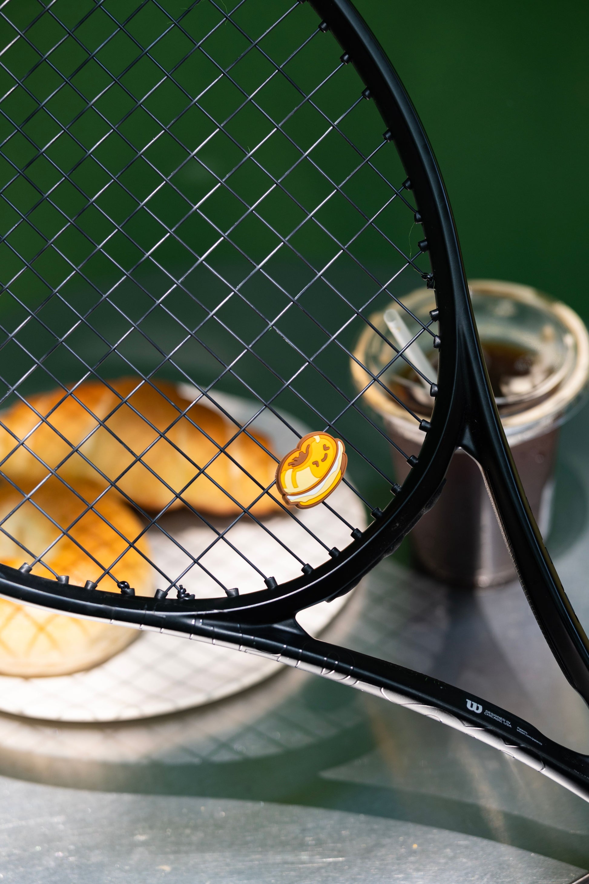 Bagel shaped tennis racket dampener photographed in lifestyle scene with wood background