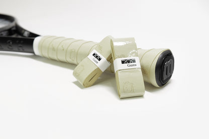 Light olive green PU tennis overgrip with cat and music note design, shown on racket handle.