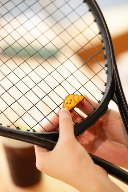 odel installing croissant shaped tennis vibration dampener on racket strings, bakery series tennis accessory