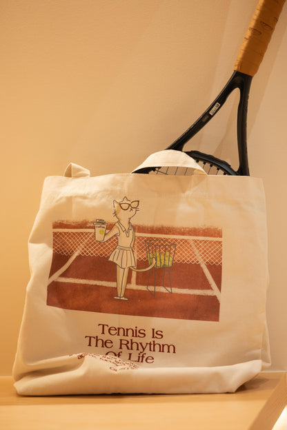 Red tennis canvas tote bag with stylish cat design, holding a tennis ball, placed on a display shelf