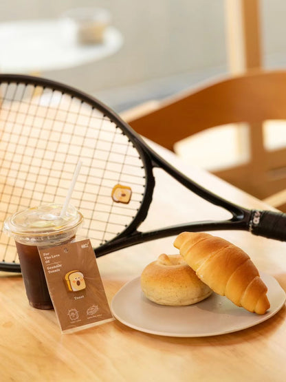 Toast shaped tennis racket dampener photographed in café lifestyle setting with coffee cup